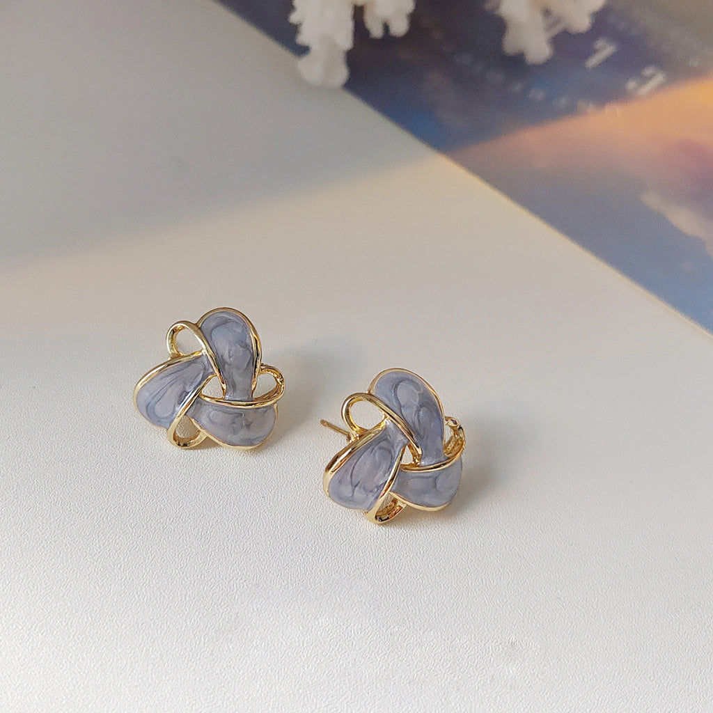 A pair of 14k gold-plated knot stud earrings with light blue-gray enamel, part of the geometric hollow-out earring set.