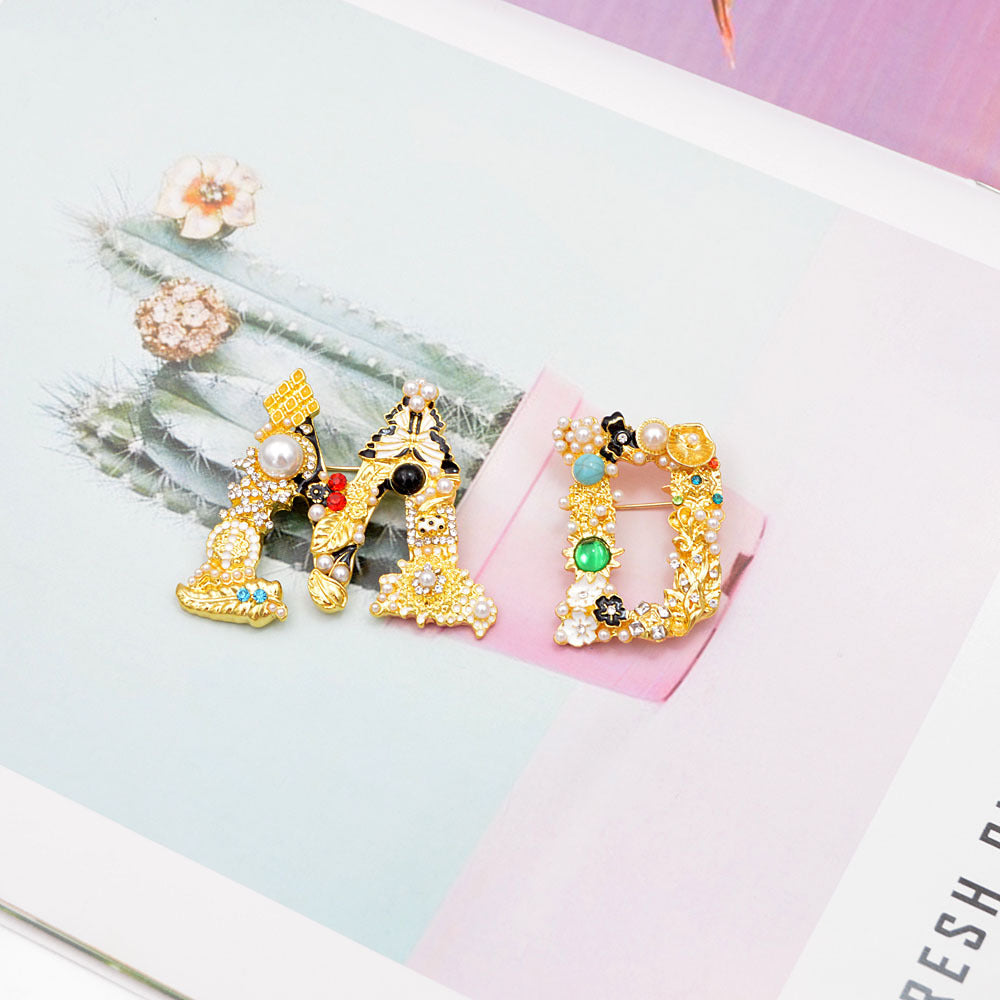 A collection of three Baroque-style letter brooches, embellished with colorful rhinestones and faux pearls, showcasing the vintage and ornate design.