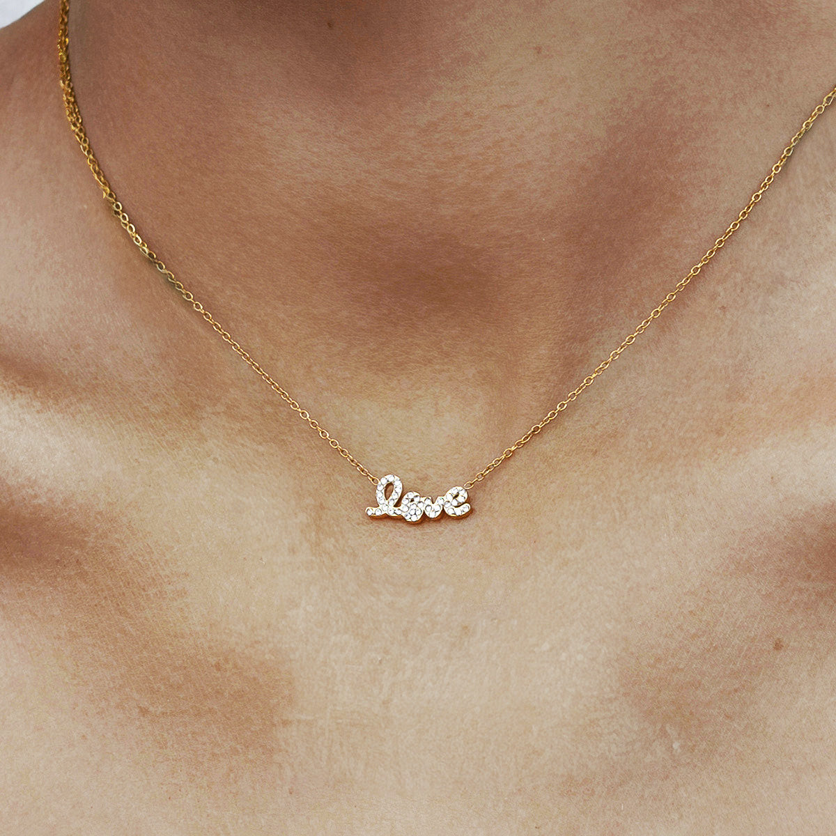 Model wearing a dainty gold love necklace with a sparkling cubic zirconia pendant, crafted from anti-tarnish stainless steel. Perfect for Valentine's Day gifting.
