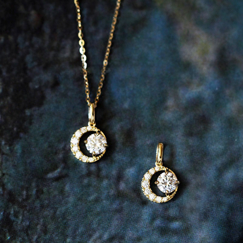 Close-up of a 925 sterling silver half-moon pendant necklace with sparkling cubic zirconia, showcasing its delicate gold-plated finish and intricate details.