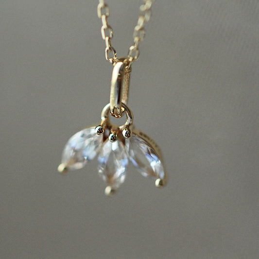 A close-up of the 925 sterling silver necklace featuring a delicate pendant with three sparkling marquise-cut zircon stones, presented on a white lace background.