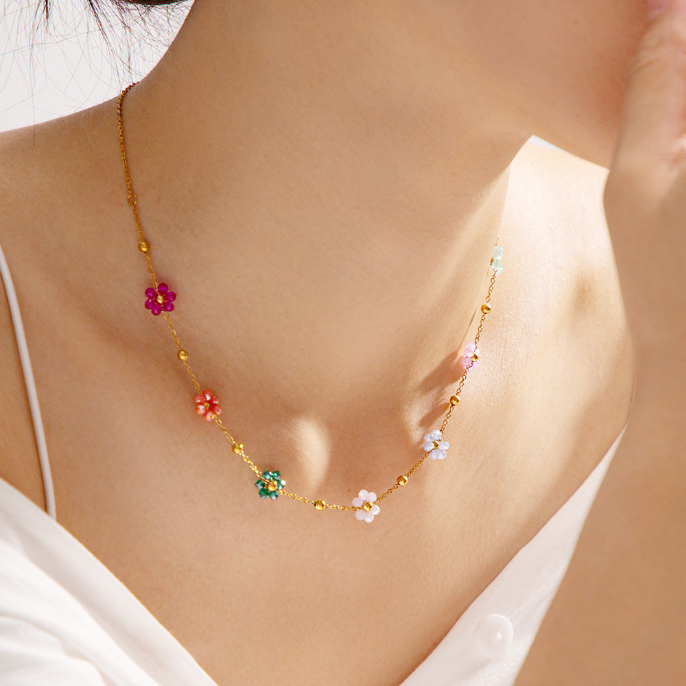 A model wearing the stainless steel gold-colored necklace featuring vibrant, colorful floral flower charms.