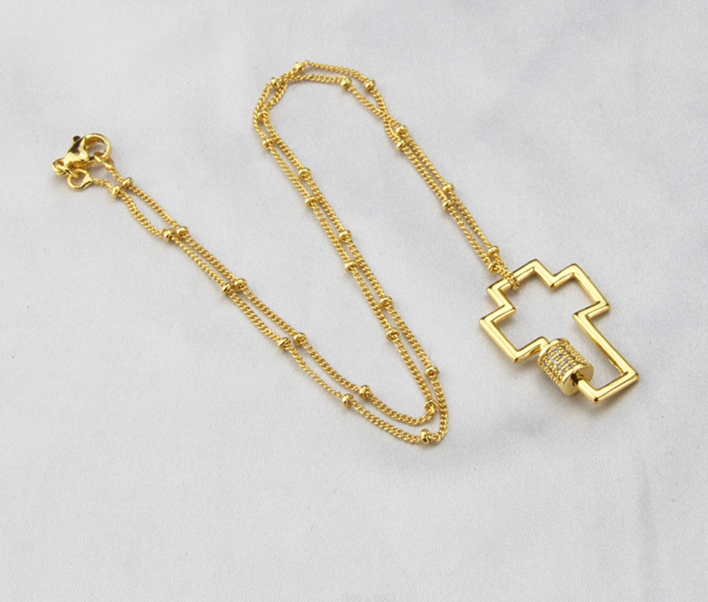 A custom-made gold cross locket charm necklace by JR Fashion Accessories, showcasing a polished cross pendant on a delicate chain, representing personalized religious jewelry.