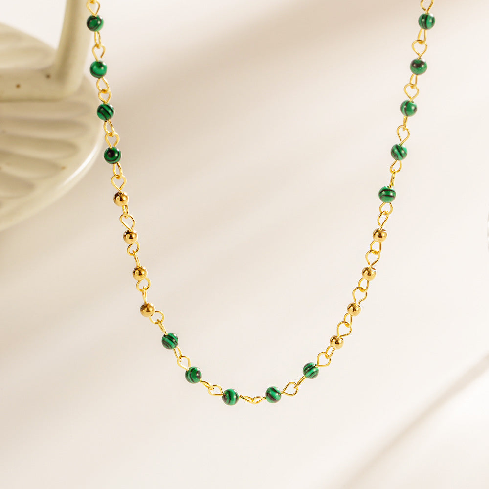 A set of 5 stainless steel necklaces with gold finish and elegant green beads, displayed on a white background.
