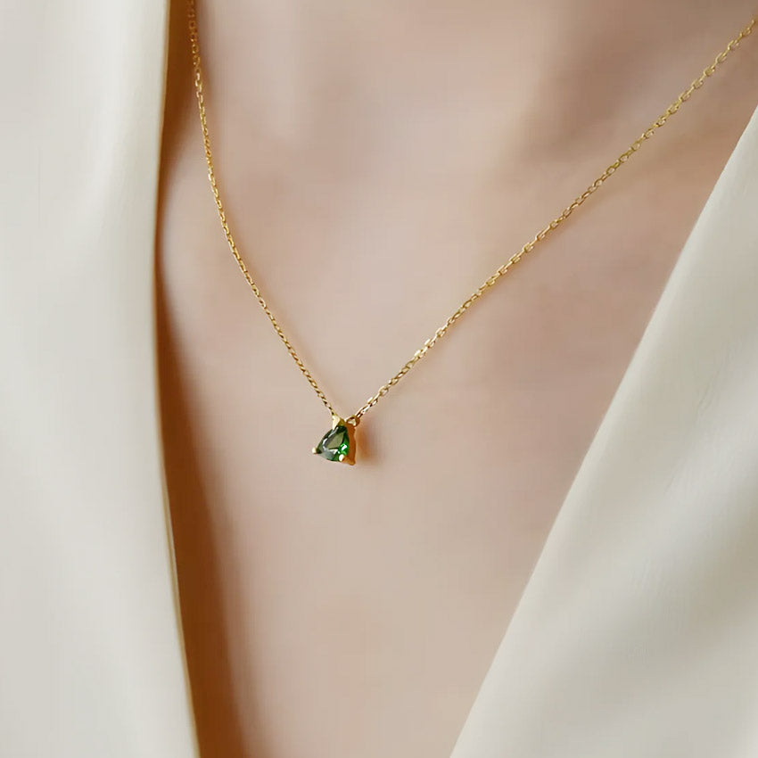 A close-up of the 925 sterling silver necklace with an 18k gold plated chain, highlighting the mini triangular green emerald stone pendant.