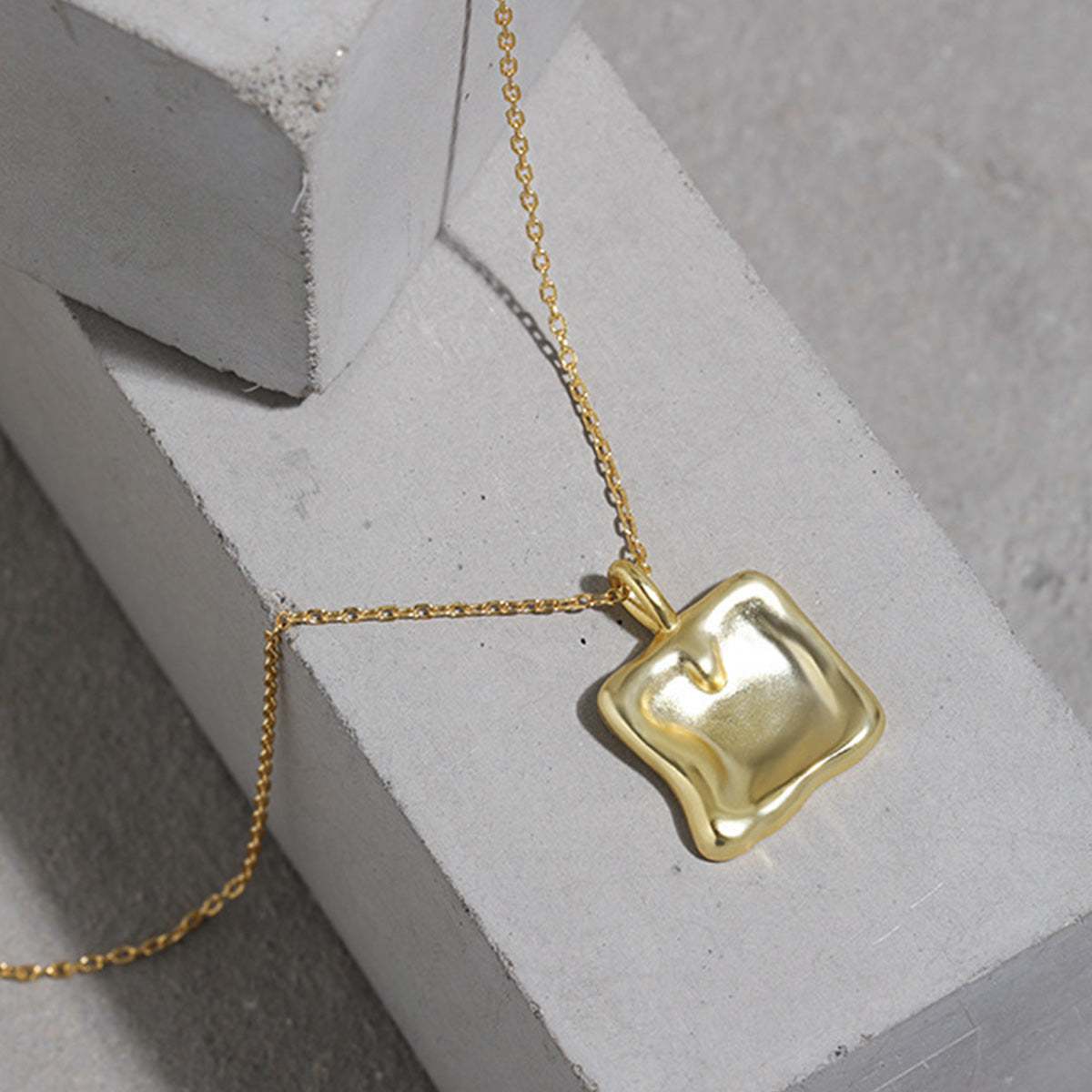 A minimalist 18K gold square charm necklace made from 925 sterling silver, featuring a unique, irregularly shaped pendant. Ideal for wholesale jewelry collections.