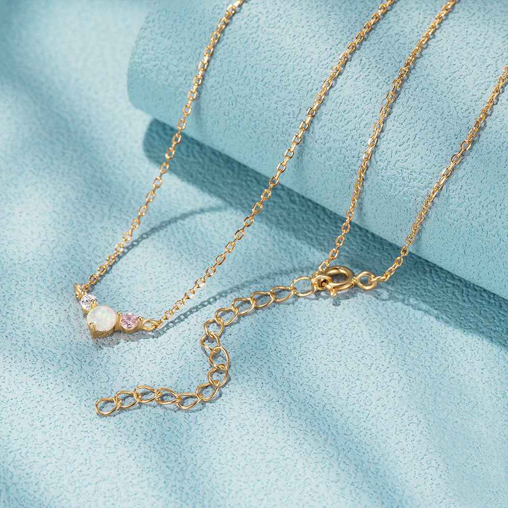 A close-up of a 925 sterling silver necklace with gold plating, featuring a delicate pendant with a central opal and sparkling cubic zirconia stones.