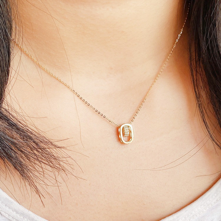 A close-up of a wholesale 925 sterling silver hollow oval pendant necklace with cubic zirconia, featuring a delicate gold-colored chain and a sparkling pendant.