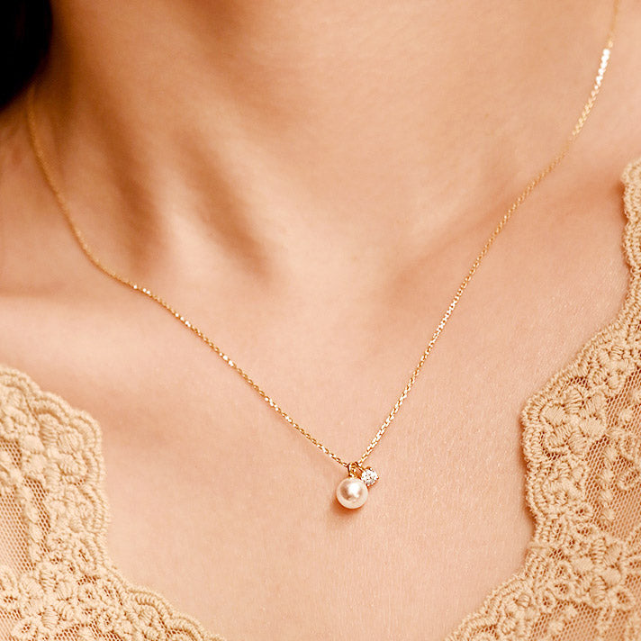 A close-up of a wholesale 925 sterling silver necklace with a single pearl and zircon stone pendant, shown in a gold finish.