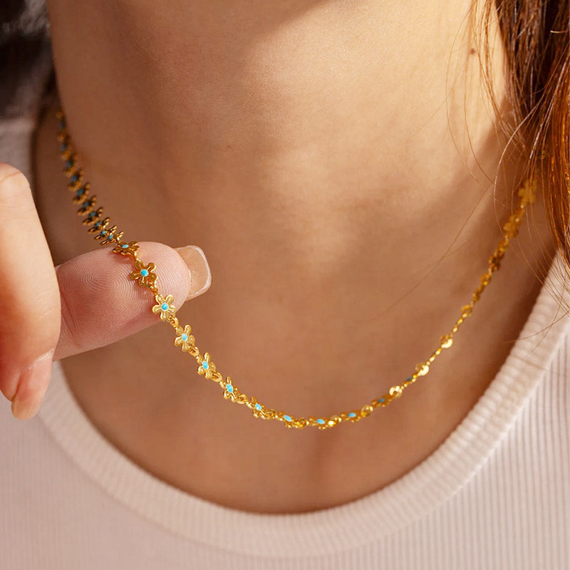 A close-up of a waterproof stainless steel necklace with delicate Bohemia blue enamel flower charms.