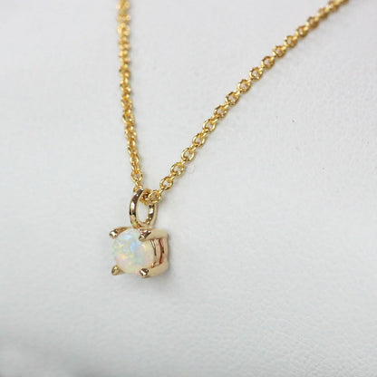 Close-up of a 925 sterling silver necklace with a gold finish, featuring a delicate 4mm round opal stone held in a classic four-claw setting.