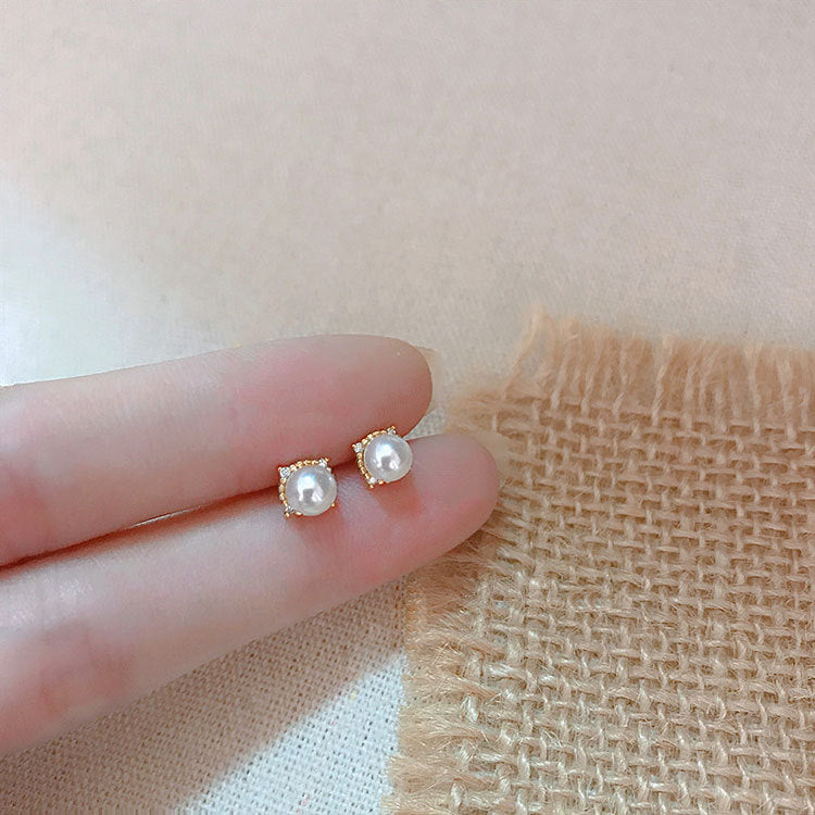 A close-up studio shot of elegant 925 sterling silver single pearl stud earrings with a polished gold finish, showcasing their classic design.