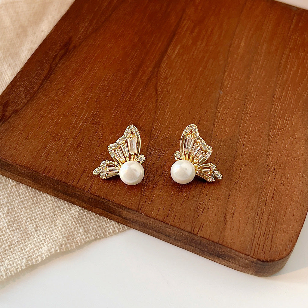A pair of gold-plated butterfly stud earrings with a central pearl and sparkling zircon gemstone accents, shown on a clean white background.