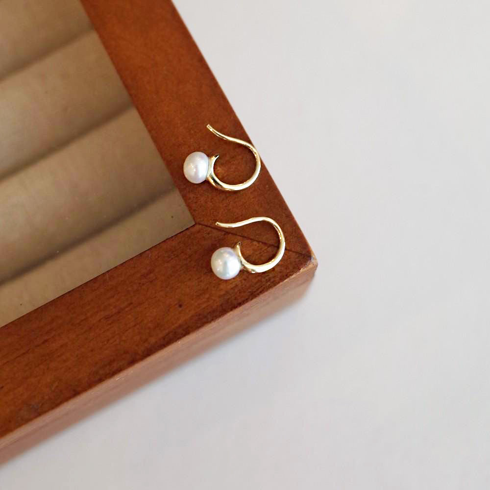A pair of elegant 925 sterling silver French style hook earrings, each featuring a single, lustrous freshwater pearl, displayed for wholesale.