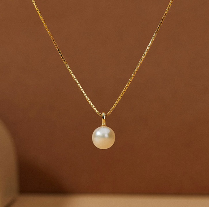 A delicate 925 sterling silver necklace with gold plating, featuring a single, elegant freshwater pearl pendant on a white background.