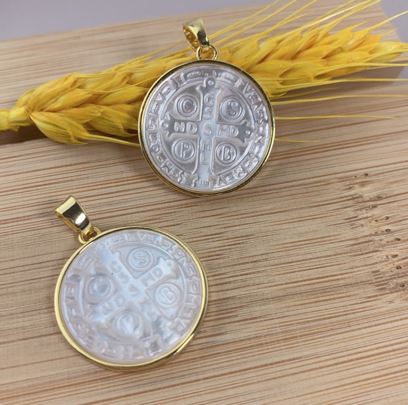 Custom Mother of Pearl Jess Mary Charms by JR Fashion Accessories, featuring two gold-framed pendants with intricate carvings on a wooden surface.