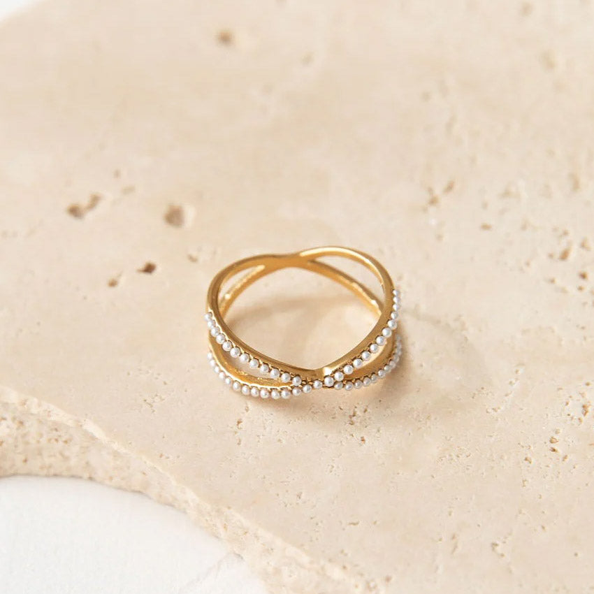 A close-up of the 18K gold plated stainless steel ring featuring a cross design with pearl accents, from the set of 5.