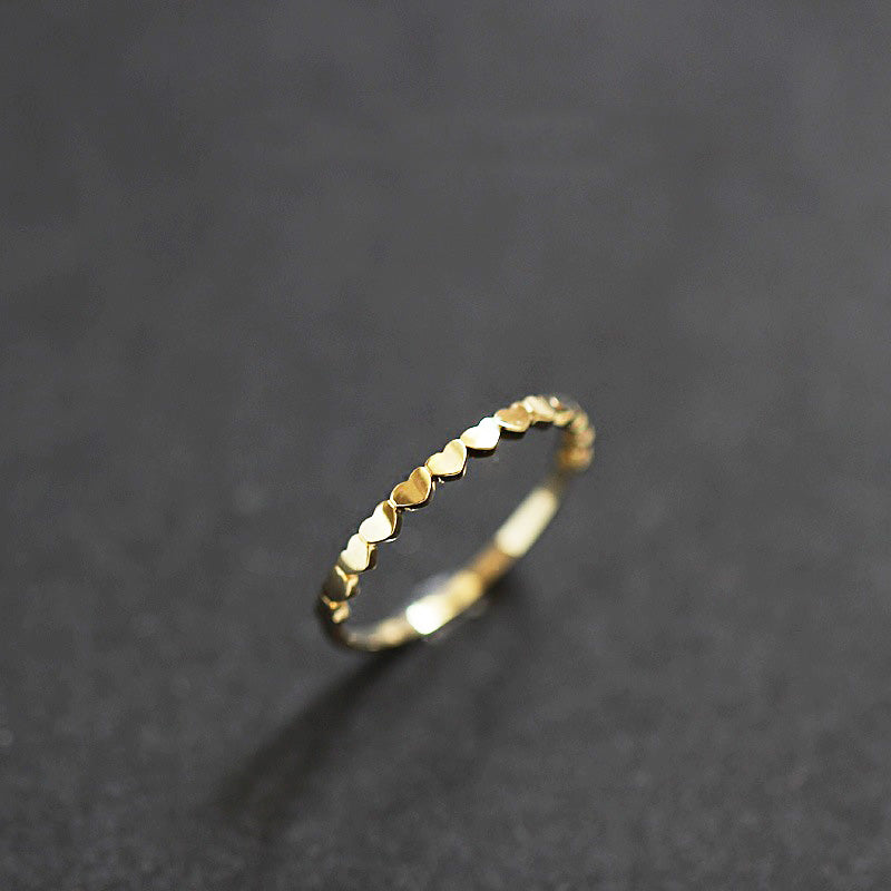 A close-up of the affordable 925 sterling silver heart link band ring, showcasing its delicate heart-shaped details in a gold finish.