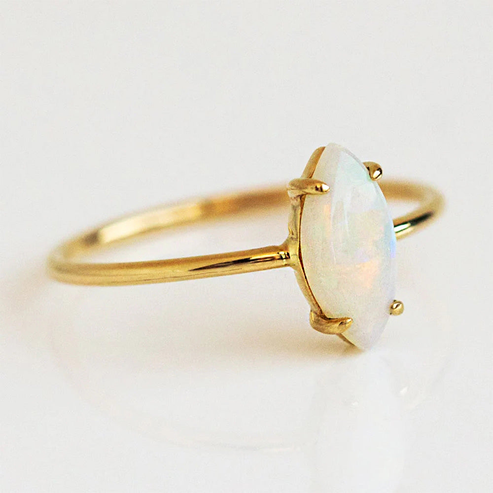 A close-up of a 925 sterling silver stackable ring with a lustrous oval opal stone, set on a delicate gold-finished band.