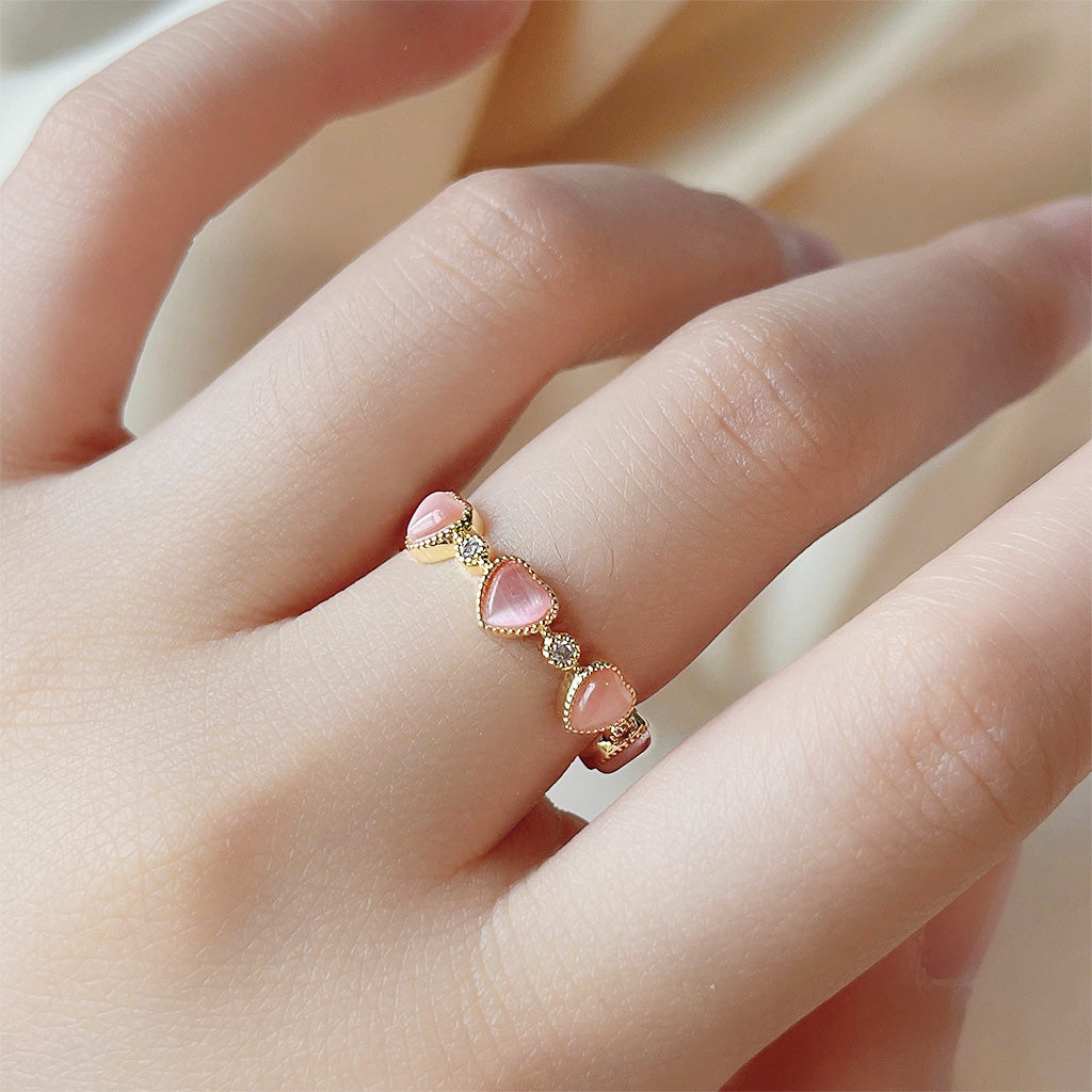 A close-up of a 14k gold plated ring from the set, featuring three pink opal stones in a delicate open band design.