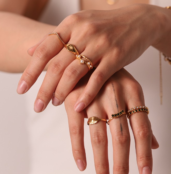 A model's hand showcasing a set of elegant gold-plated layered rings with cubic zirconia from JR Fashion Accessories.