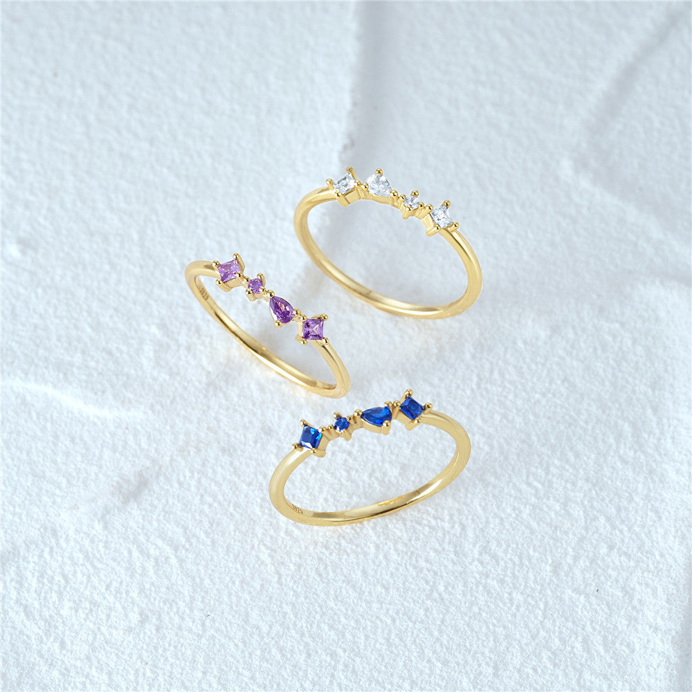 A set of three 925 sterling silver stacking rings in a gold finish, each adorned with a row of four zircons in purple, blue, and white.