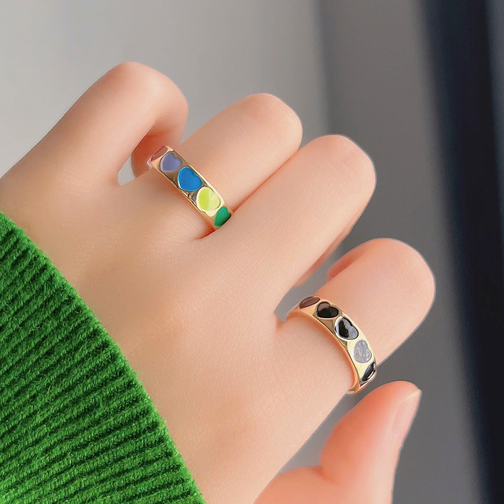 A set of five gold-plated heart pattern enamel open finger rings, with two rings featured prominently showing colorful and monochrome stone details.