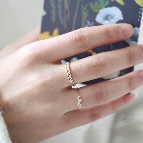 A woman's hand showcasing the elegant 925 Sterling Silver Hollow Zircon Minimalist Engagement Rings set, with a floral card in the background.