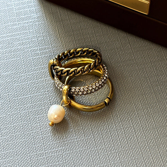 A stylish collection of wholesale brass rings from JR Fashion Accessories, featuring a set of three gold-toned rings with a delicate pearl pendant.