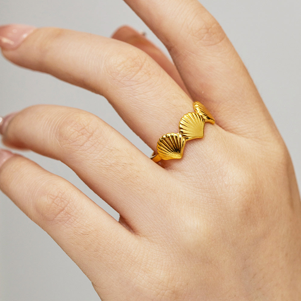A hand wearing the gold-colored stainless steel ring from the triple shells beach jewelry set.