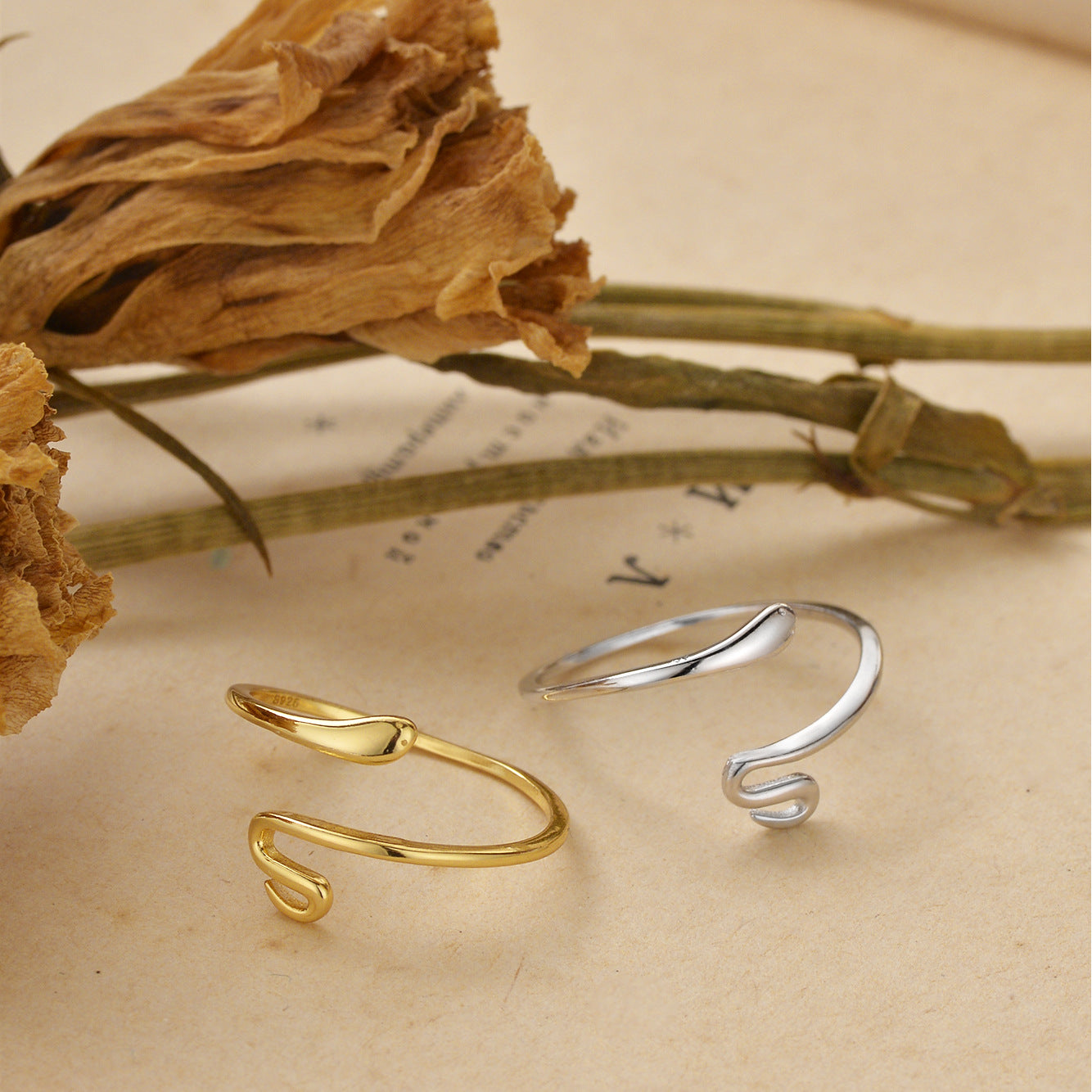 A minimalist adjustable serpent ring in both 925 sterling silver and gold-tone finishes, styled on a neutral background to showcase its sleek, modern design.