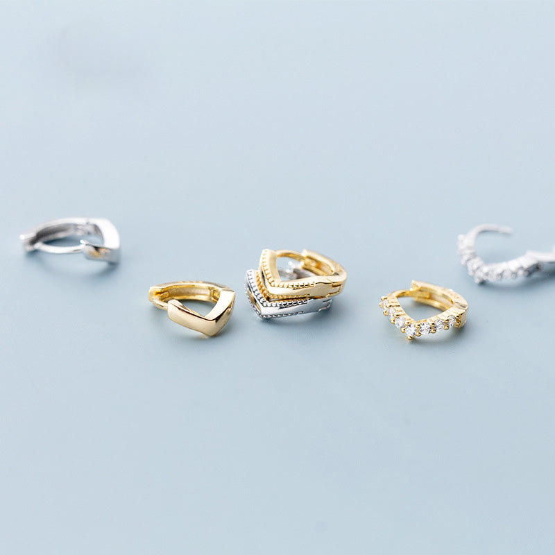 A collection of Sterling Silver Tiny Wave V-Shape Huggie Helix Hoop Earrings, displayed in both gold and silver finishes and various styles.