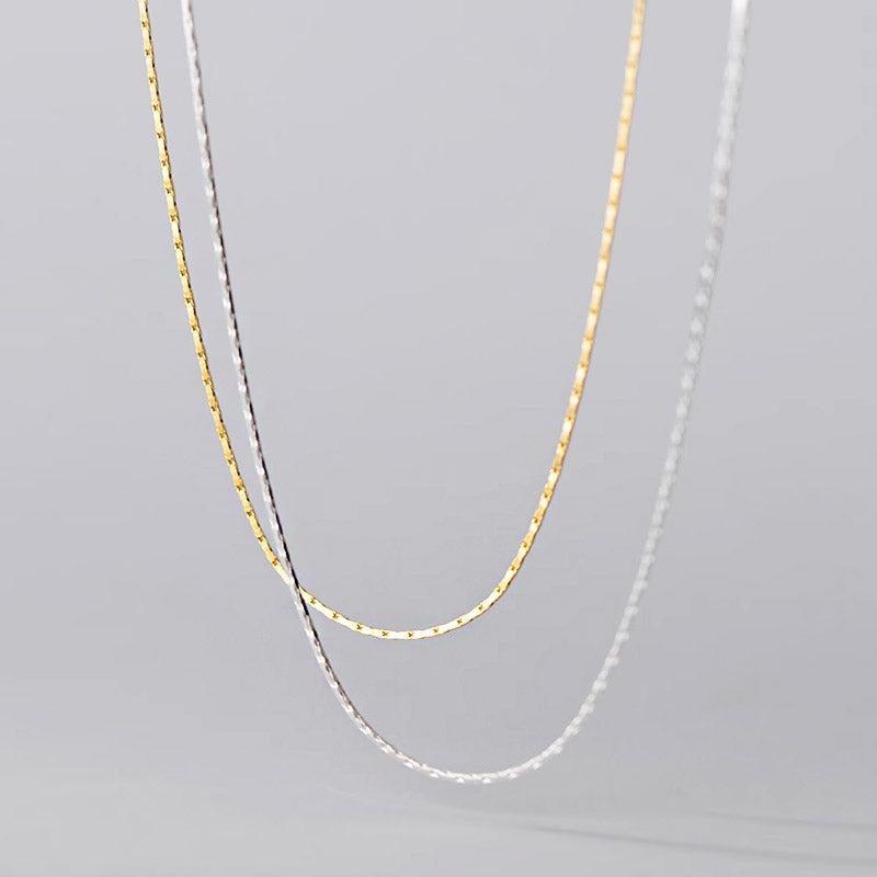 A close-up product shot of the 925 sterling silver super thin snake chain necklaces, showcasing both the gold and silver finishes and their delicate texture.