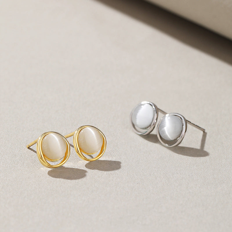 A stylish set of 925 sterling silver stud earrings with white cat-eye stones, displayed in both polished silver and radiant gold finishes.