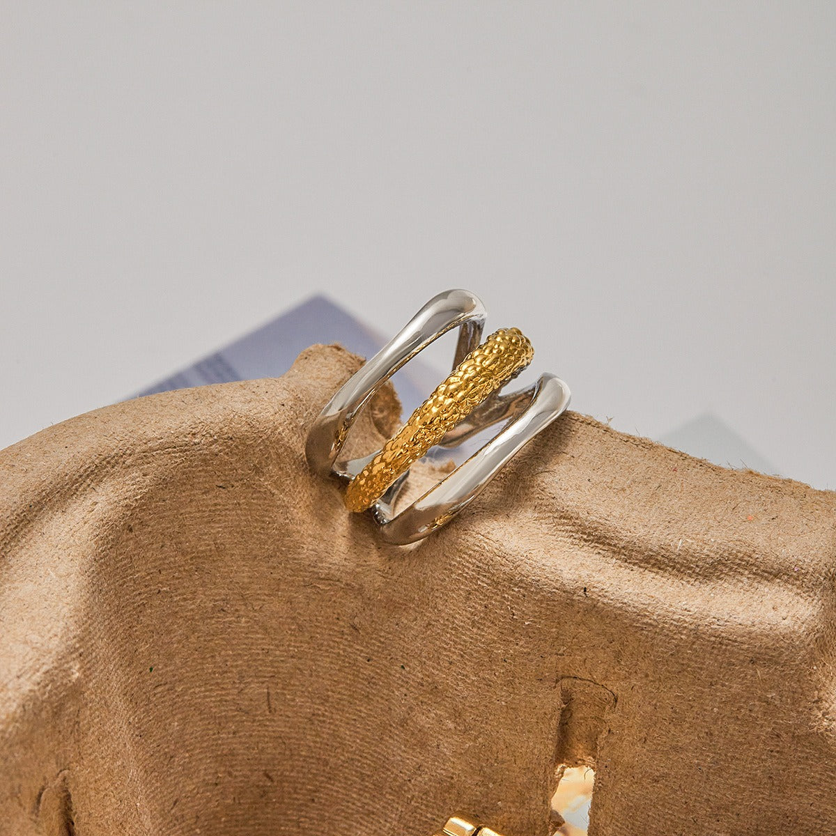 A set of five two-tone stainless steel rings in gold and silver, showcasing varied textures and modern designs, perfect for stacking and daily wear.