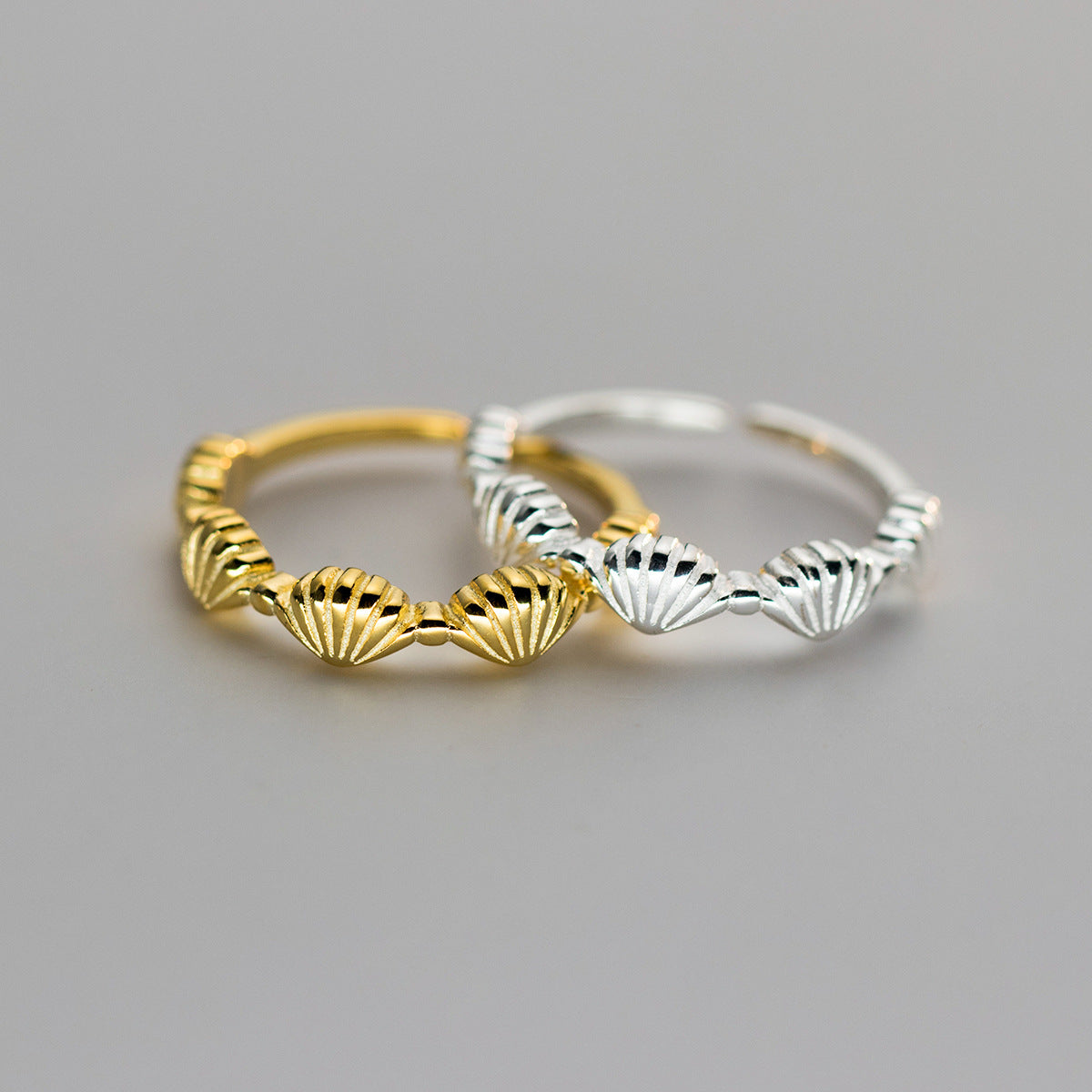 A stunning set of two 925 sterling silver rings with a seashell design, one plated in gold and the other in polished silver, showcasing the adjustable feature.