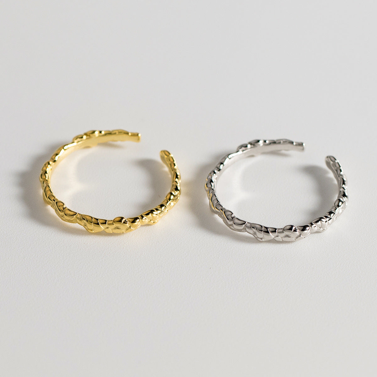 A pair of 925 sterling silver adjustable braided rings, one in a polished silver finish and the other in a radiant gold finish.