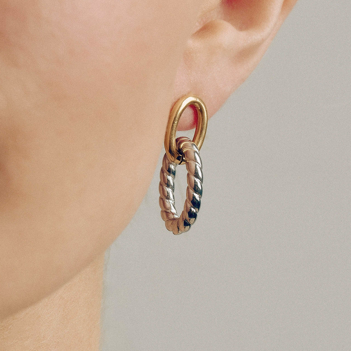 Model wearing the chunky two-tone oval twist earrings, showcasing the elegant gold and silver design on hypoallergenic stainless steel.