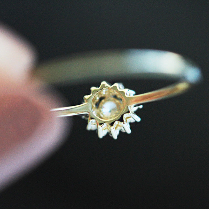 A close-up of a 925 sterling silver sunflower ring with a gold finish, featuring a central cubic zirconia surrounded by sparkling petals in a sunburst design.