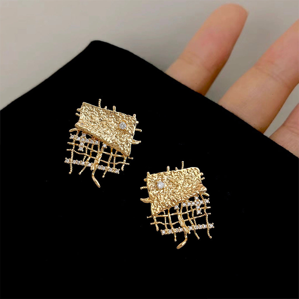 A pair of geometric statement earrings in gold, featuring a textured grid pattern with sparkling micro-paved CZ stones.