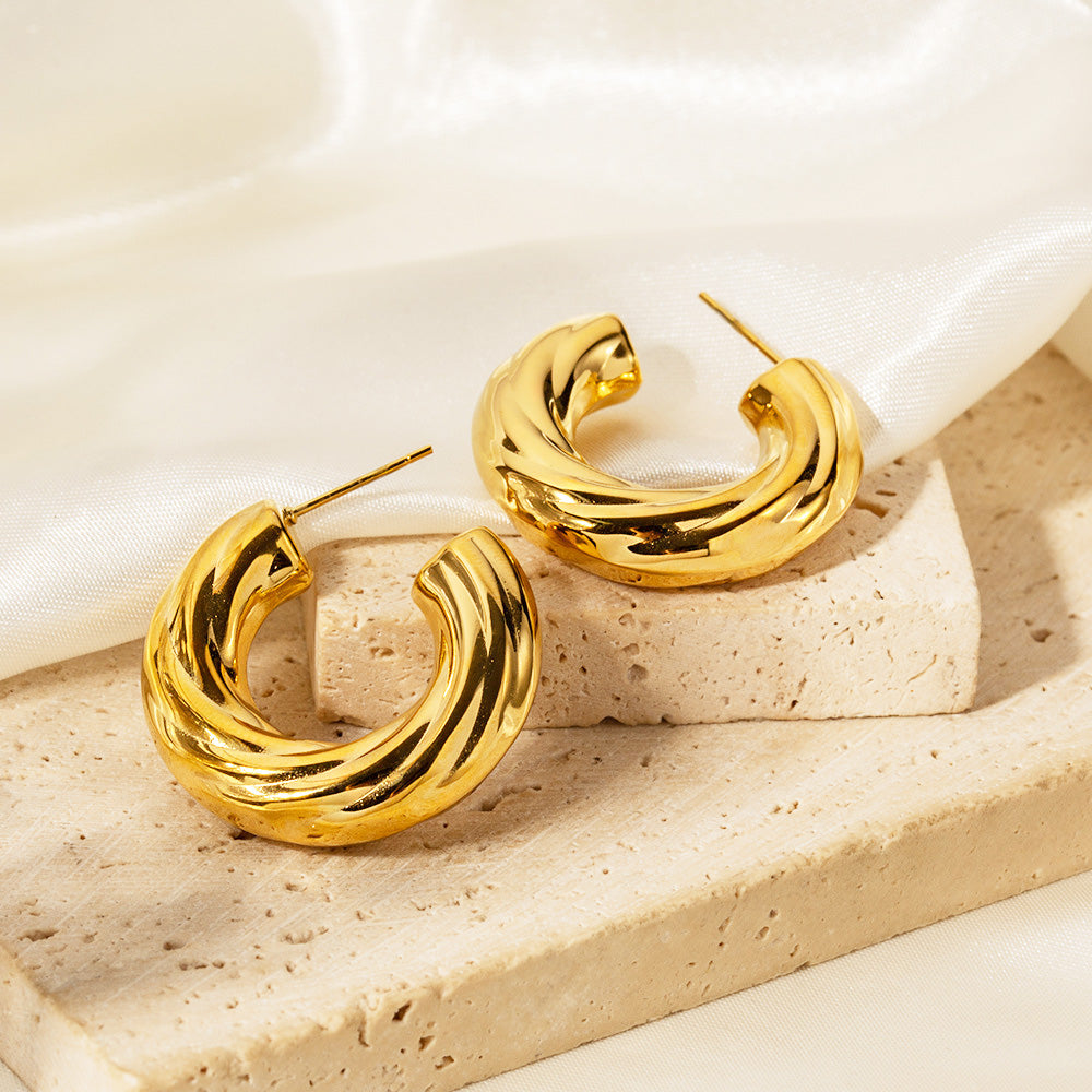 A pair of stainless steel retro gold-plated twisted C-shape stud earrings on a clean white background, showcasing their intricate design.