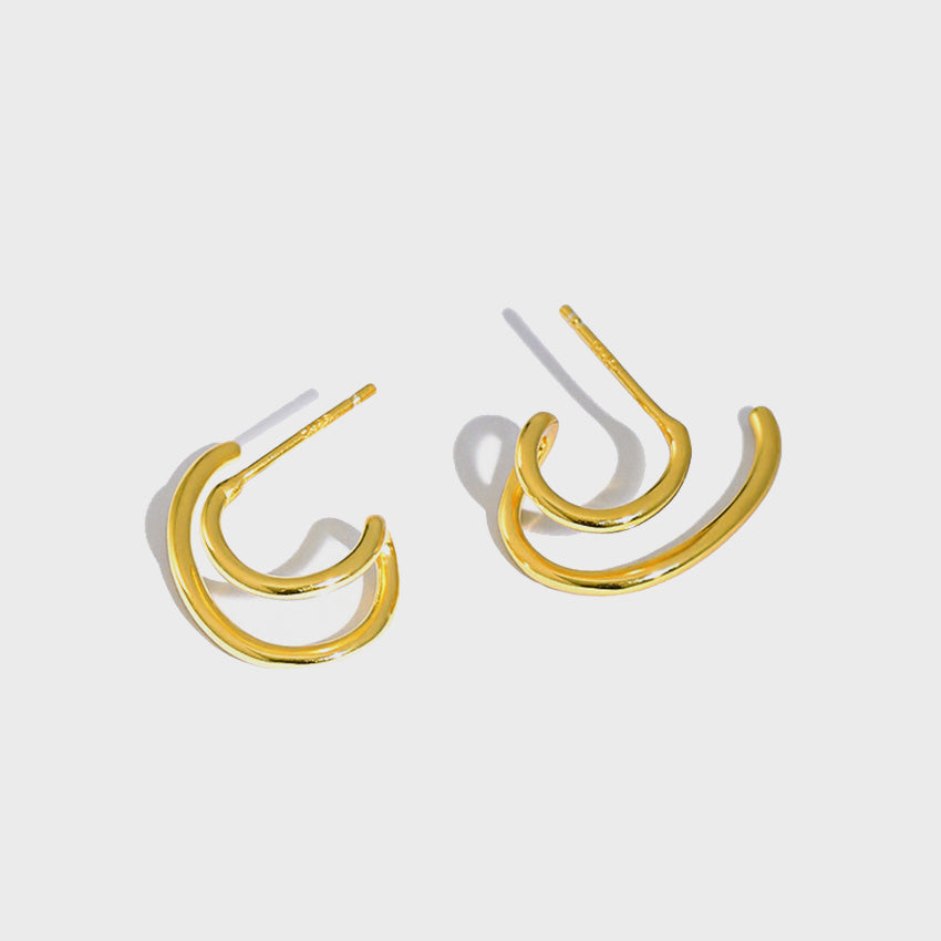 A studio product shot of the 18K gold-plated 925 sterling silver Double C hoop stud earrings, showcasing their minimalist U-shaped design and shiny finish against a white background.
