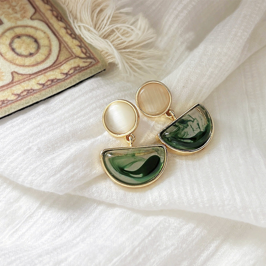 A pair of delicate vintage drop earrings with green and white opal-like stones set in a polished gold-tone brass frame.