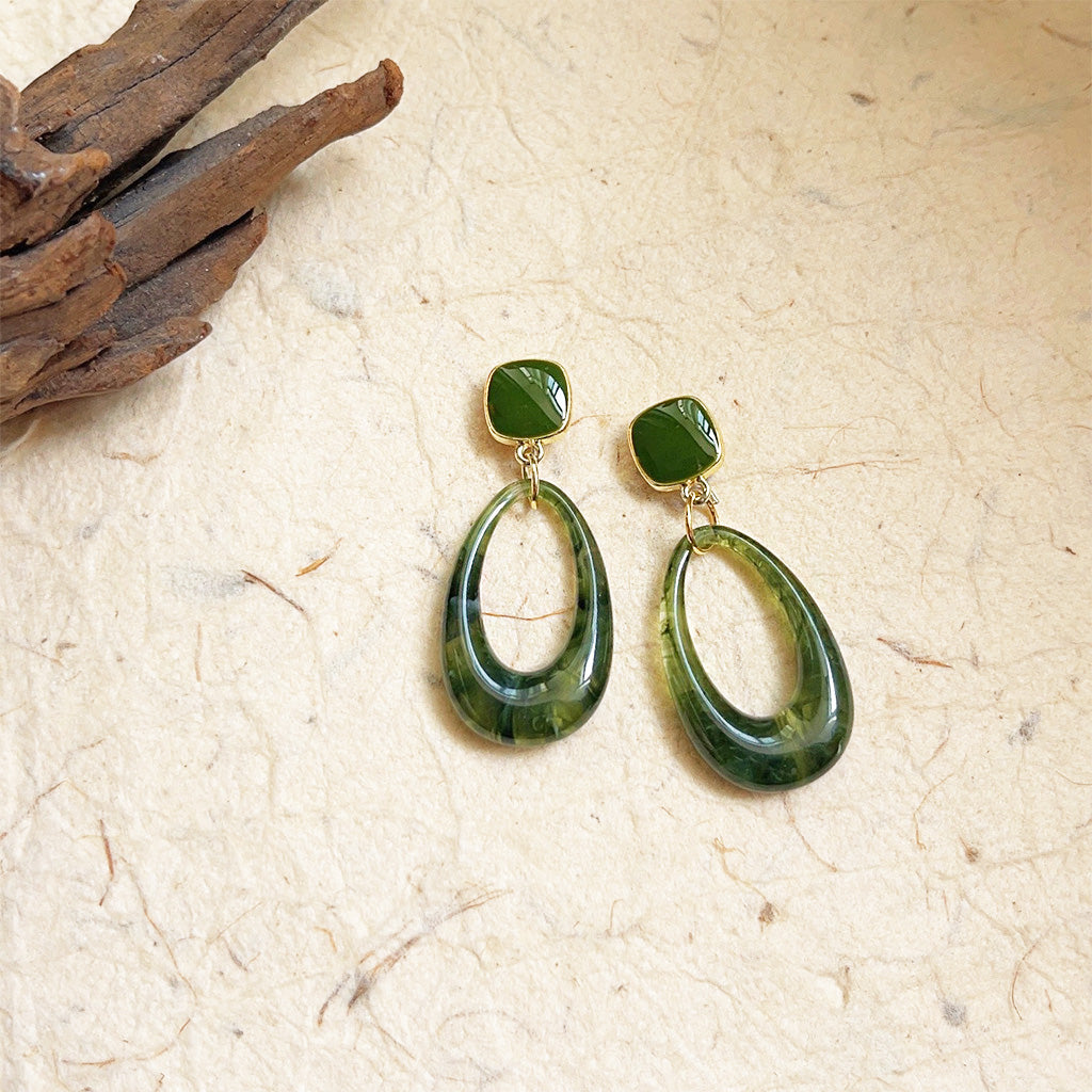 A pair of vintage-style 14k gold-plated drop earrings featuring a square top and a teardrop-shaped green resin stone with natural marbling.