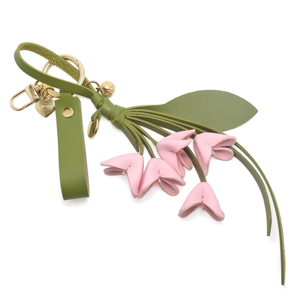 A stylish pink PU leather orchid flower bag charm with a green strap and gold clasp, perfect as a wholesale keychain or purse accessory.