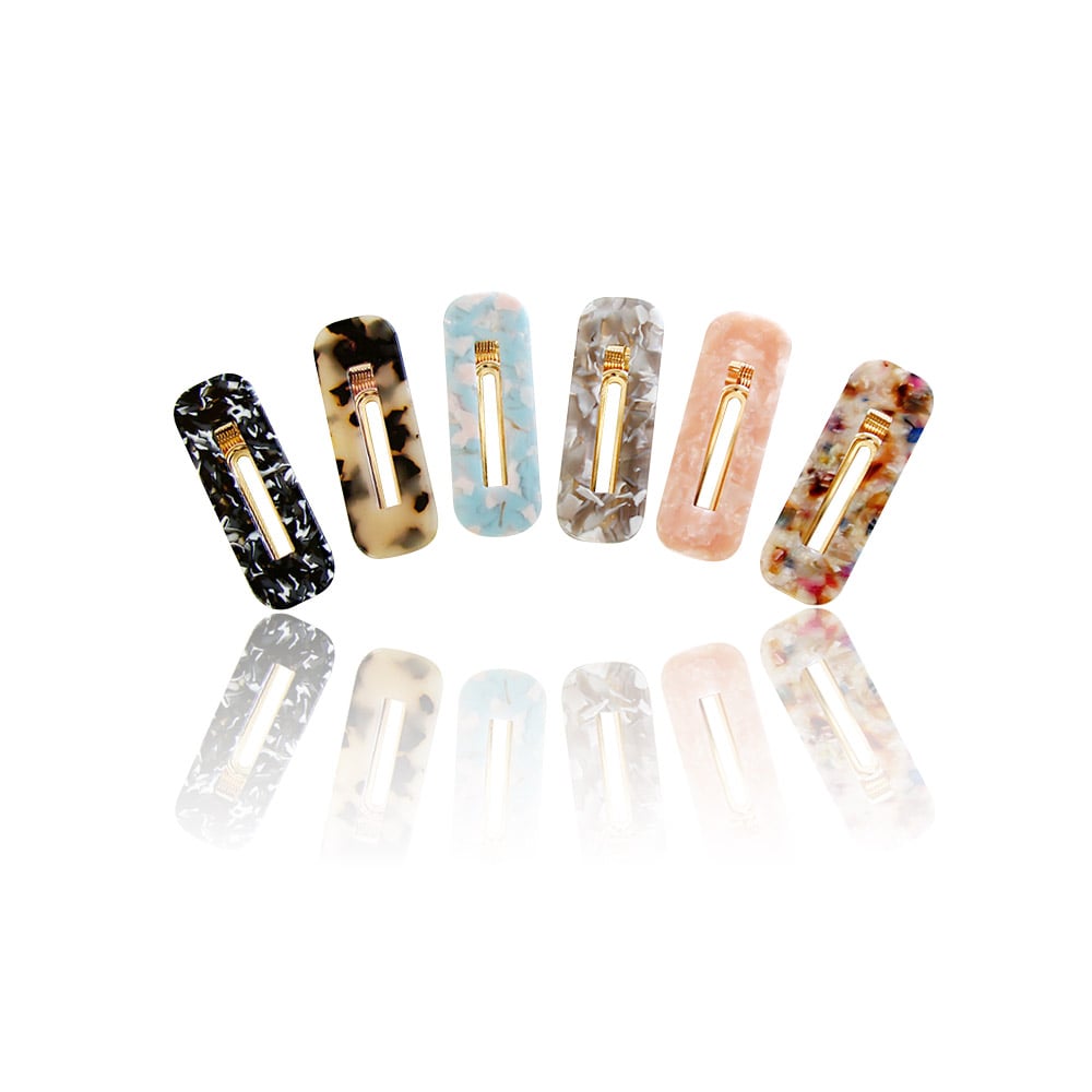 A collection of six rectangular tortoise shell hair clips in various marbled patterns, each with a central gold metal accent.