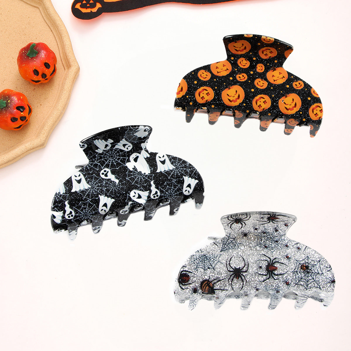 A collection of glittery Halloween-themed hair claw clips featuring spooky designs like ghosts, spiders, and pumpkins.