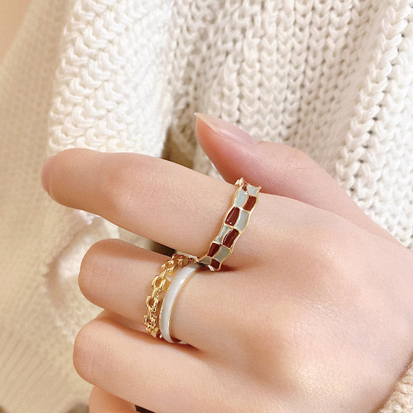 A model's hand wearing the stylish gold-plated enamel checkerboard adjustable open rings, showcasing the set of 5.