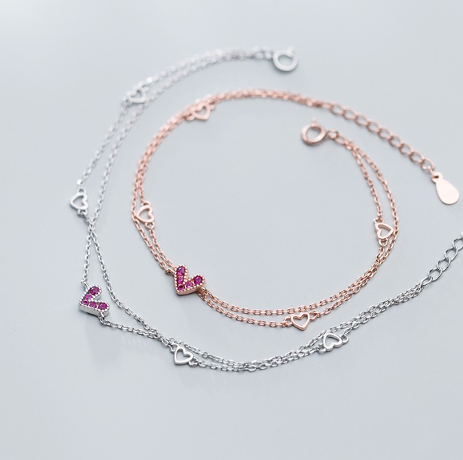 A pair of 925 sterling silver heart bracelets, one in rose gold with pink cubic zirconia and the other in silver with clear gems, elegantly displayed.