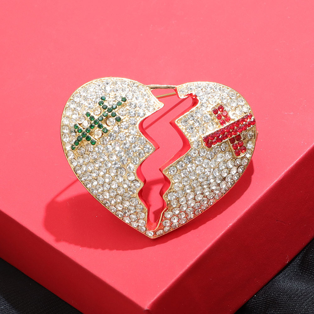 Front view of the Rhinestone Cracked Heart Brooch, showcasing its gold-colored alloy, broken heart design, and full encrusting of clear rhinestones with subtle red and green accents.